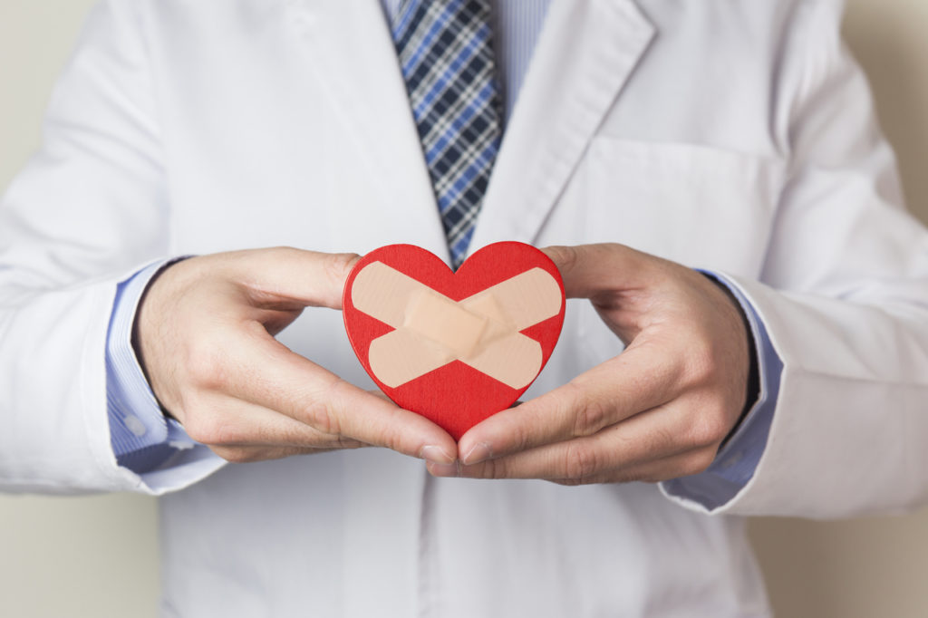 A doctor holding a heart with band aids