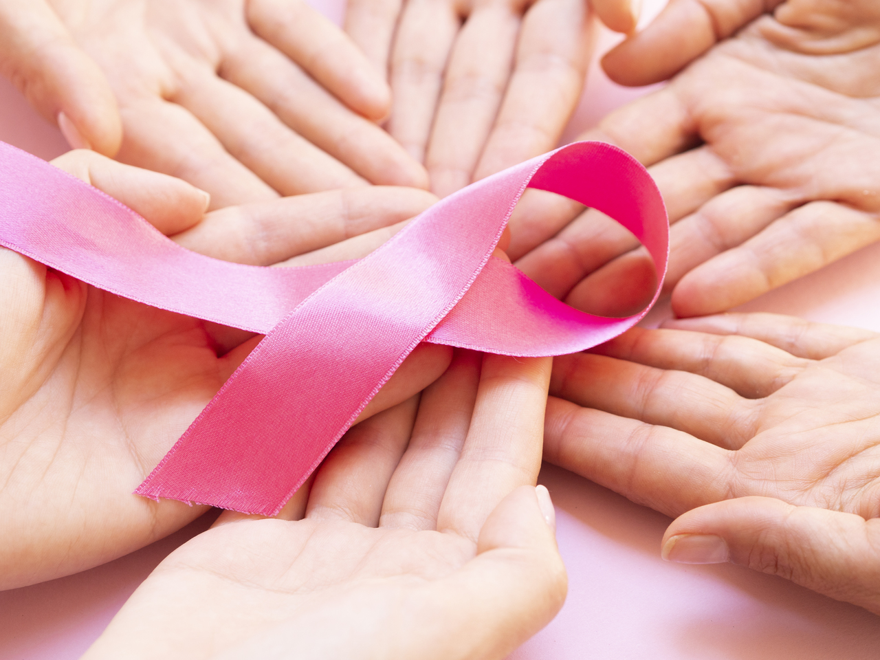 Hand holding a ribbon in the symbol of breast cancer