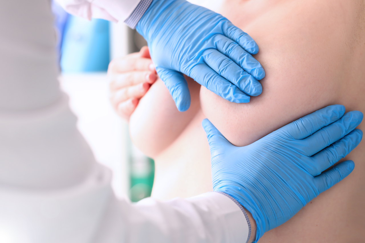 A doctor wearing gloves giving their patient a breast examination