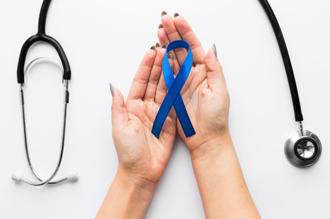 A hand holding colon cancer blue ribbon